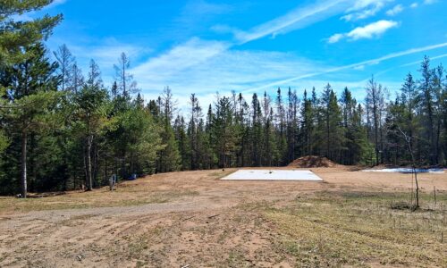 Wooded 8-acre property for sale in Rhinelander with mature trees, direct access to adjoining Wisconsin State Land, and 30x50 concrete pad ready for construction.
