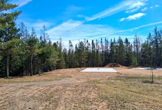 Wooded 8-acre property for sale in Rhinelander with mature trees, direct access to adjoining Wisconsin State Land, and 30x50 concrete pad ready for construction.