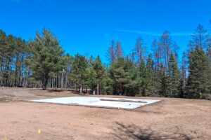 Wooded 8-acre property for sale in Rhinelander with mature trees, direct access to adjoining Wisconsin State Land, and 30x50 concrete pad ready for construction.